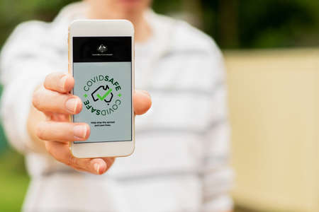 Sydney, Australia 2020-04-26 Hand holding a white smartphone with CovidSafe app. Australian Government introduced new COVID-19 trace tracking appのeditorial素材