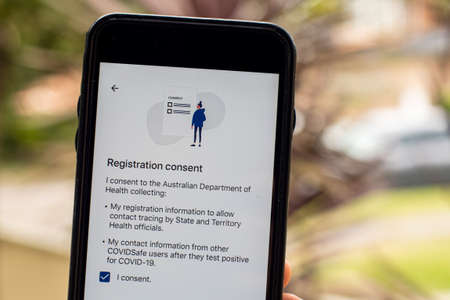 Sydney, Australia 2020-04-26 Hand holding a phone with CovidSafe app. Registration consent screen. Australian Government introduced new COVID-19 trace tracking appのeditorial素材