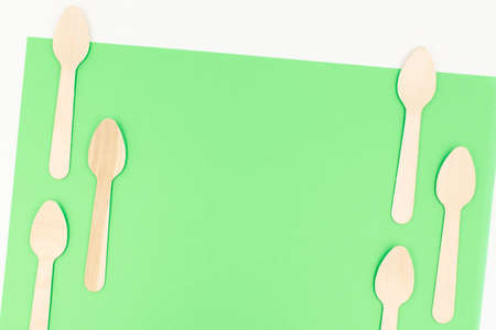 Eco friendly disposable cutlery utensils on green background with copy space. Bamboo wooden tea spoons. Zero waste conceptの写真素材