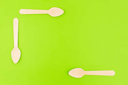 Eco friendly disposable cutlery utensils on green background. Bamboo wooden tea spoons. Zero waste conceptの写真素材