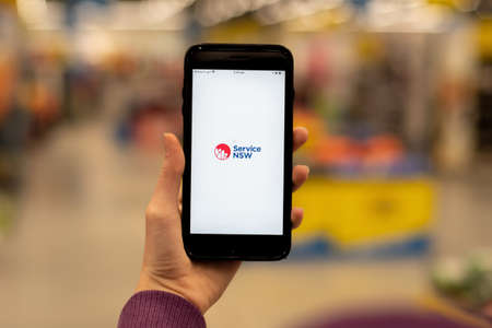Sydney, Australia 2020-08-07 Hand holding a phone with Service NSW app. Service NSW repurpose its app for contact tracingのeditorial素材