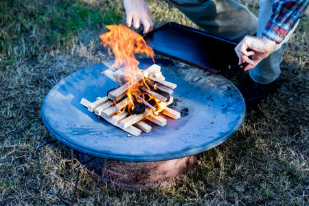 Starting the camp fire with kindling to cook breakfast on cast iron plate. Camping lifeの写真素材
