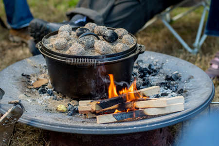 Dutch oven campfire cooking with coal briquettes on top, Camping life.の写真素材