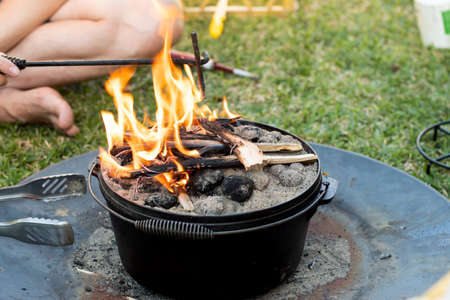 Dutch oven campfire cooking with coal briquettes and flame on top, Camping life.の写真素材