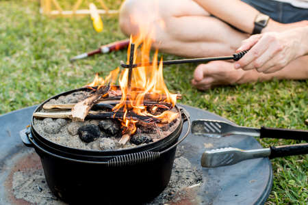 Dutch oven campfire cooking with coal briquettes and flame on top, Camping life.の写真素材