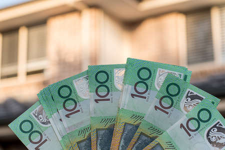 Australian dollars 100 banknotes with blurred resedential building on background. Finance and mortgage concept.の写真素材