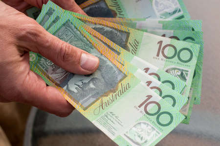 Hand holding australian dollars 100 banknotes on glass table background. Finance and payment concept.の写真素材