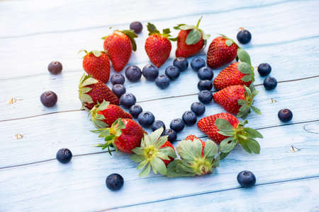 Blueberry and strawberry heart on a wooden background. Valentines day concept.