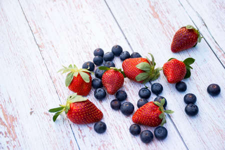 Blueberries in a bowl and some strawberries on a wooden background. Healthy lifestyle conceptの写真素材