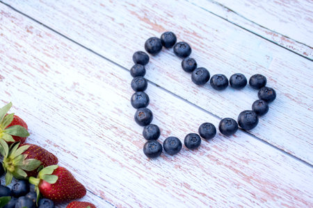 Blueberry heart and some strawberries on a wooden background. Valentines day concept.の写真素材