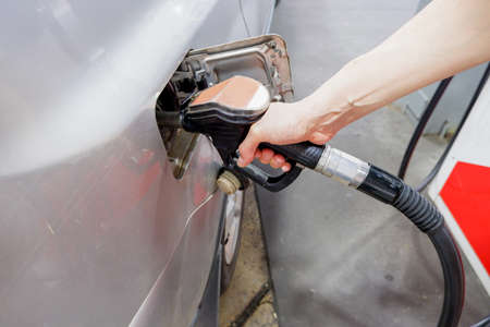 A man hand holding pump filling gasoline. Pumping petrol into the tank. A car refuel on gas station