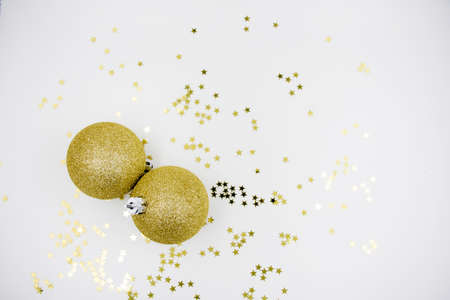 Two golden christmas balls baubles on a white background with blurry golden stars. Festive season backgroundの写真素材