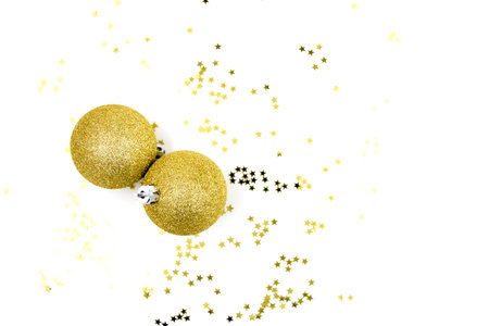 Two golden christmas balls baubles on a white background with blurry golden stars. Festive season backgroundの写真素材