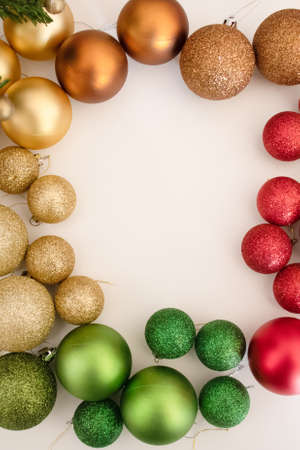 Christmas balls baubles on a light background laying by colours - gold, red, green. Empty space for text inputの写真素材