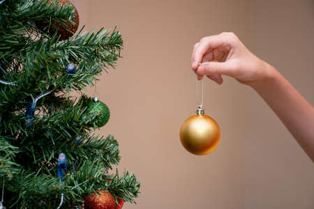 Hand holding christmas ball bauble to decorate the christmas treeの写真素材