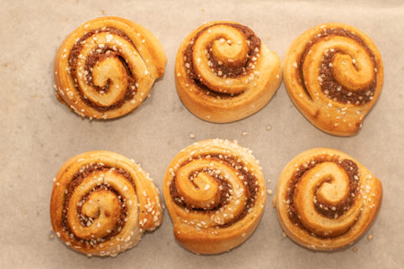 Freshly baked cinnamon buns rolls on a tray lined with baking parchment paper. Baking at homeの写真素材
