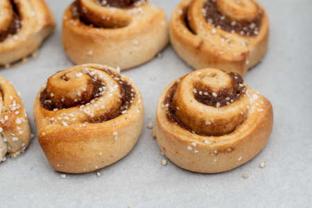 Freshly baked cinnamon buns rolls on a tray lined with baking parchment paper. Baking at home