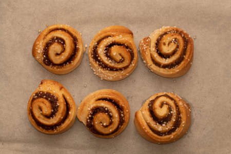 Freshly baked cinnamon buns rolls on a tray lined with baking parchment paper. Baking at homeの写真素材