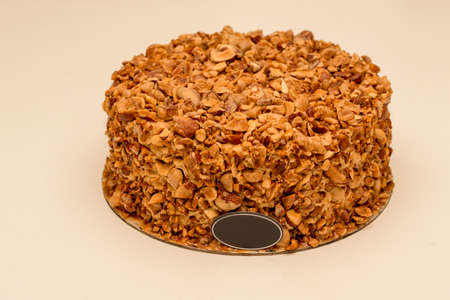 Beatiful nut biscuit cake finished with crushed sugar-coated candied caramelized almonds on a white tableの写真素材