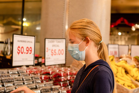 Wearing face masks in shopping centres are compulsory in Greater Sydney NSW. Young adult girl wearing disposable face mask at the grocery store. Covid-19 restrictionsの写真素材