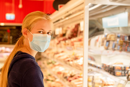Wearing face masks in shopping centres are compulsory in Greater Sydney NSW. A girl wearing disposable face mask at the supermarket. COVID-19 restrictions.の写真素材