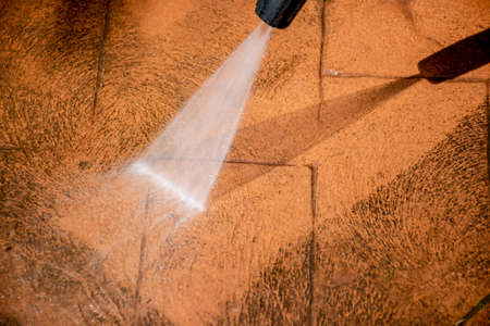 Cleaning backyard paving tiles pathway with high pressure washer. Spring clean up