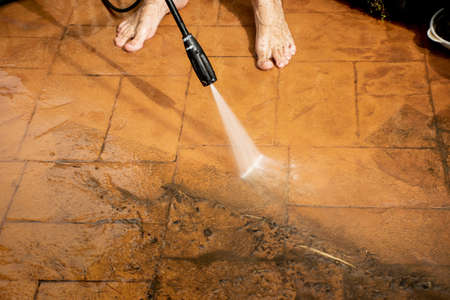 Selective focus. Cleaning backyard paving tiles with high pressure washer. Spring clean upの写真素材