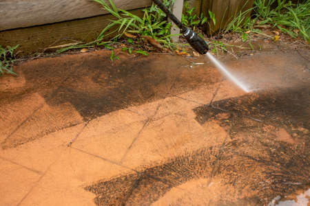 Selective focus. Cleaning backyard paving tiles with high pressure washer. Spring clean upの写真素材
