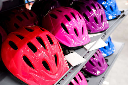 Various colors bike helmets on sport store display. Bicycle safety accesories shoppingの写真素材