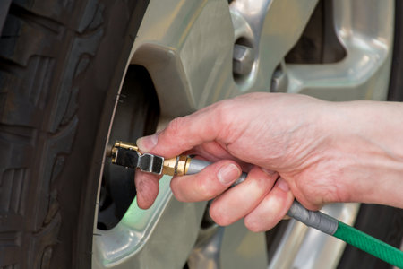 Hand holding pressure gauge, checking air pressure and filling air in the tires of the car. Car maintenance. Checking tyre air pressure before travelの写真素材