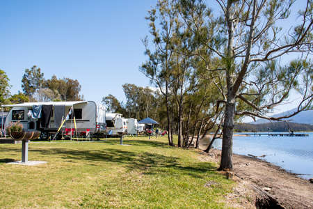 RV caravans camping at the caravan park on a peaceful lake with mountains on the horizon. Camping vacation family travel conceptの写真素材