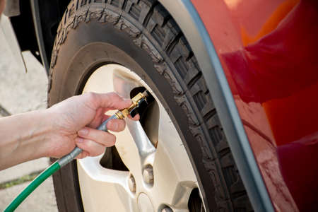 Hand holding pressure gauge, checking air pressure and filling air in the tires of the car. Car maintenance. Checking tyre air pressure before travelの写真素材