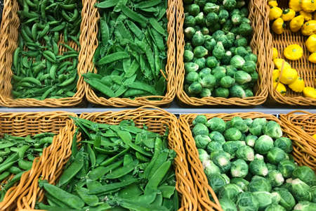 Fresh Brussel sprouts, green peas, yellow squash patty pan patisson piled in the baskets on the market. Food background. Harvestの写真素材