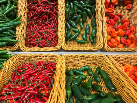 Fresh chillies variety piled in the baskets on the market. Green Cayenne, Red Chilli, Habanero Chilli, Jalapeno pepper. Food background. Harvestの写真素材