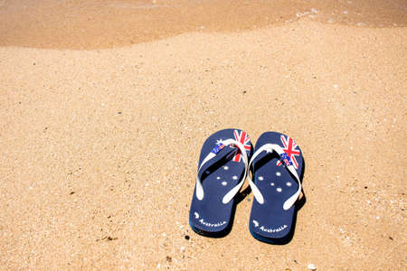 Australia Day and travel destination background: patriotic Aussie thongs featuring Australian flag on the beautiful on the sandの写真素材