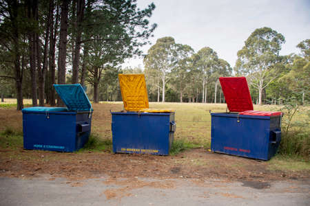 Australian garbage bins with colourful lids for recycling, paper and cardboard and general waste suttounding by the nature in a bush forest outdoors locationの写真素材