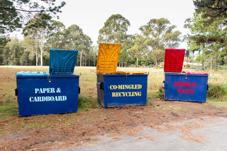 Australian garbage bins with colourful lids for recycling, paper and cardboard and general waste suttounding by the nature in a bush forest outdoors locationの写真素材