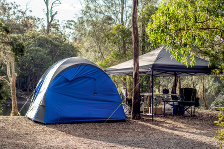 Tent setup with gazebo canopy shelter at the campsite surrounding by nature on the river bank. Camping and recreationの写真素材