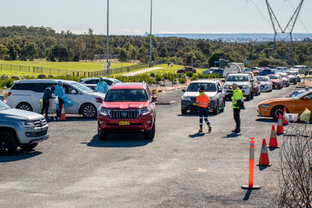 Barden Ridge, Australia - 2021-07-18 Medical stuff making covid test swab at COVID-19 drive through testing clinic. Long vehicle queue.のeditorial素材