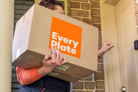 Sydney, Australia 2020-05-09 Delivery man holding Every Plate meal kits in a box near the front doorのeditorial素材