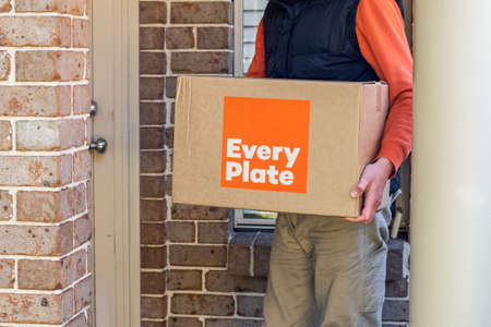 Sydney, Australia 2020-05-09 Delivery man holding Every Plate meal kits in a box near the front doorのeditorial素材