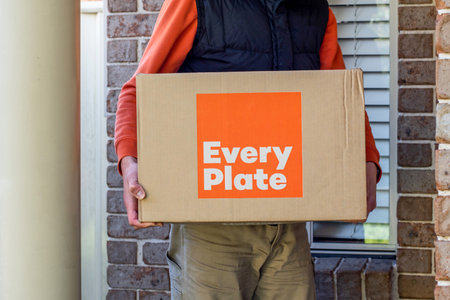 Sydney, Australia 2020-05-09 Delivery man holding Every Plate meal kits in a box near the front doorのeditorial素材