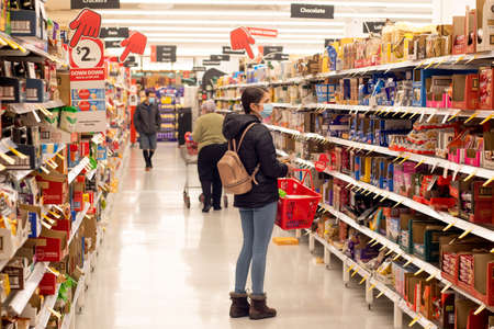 Sydney, Australia 2021-07-21 Teenage girl man wearing mask surveying grocery aisle at Coles supermarket during pandemic Delta outbreak lockdown.のeditorial素材