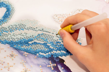 Diamond painting embroidery craft. Acrylic rhinestones and pen tool. Closeup, selective focusの写真素材
