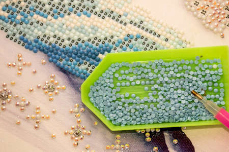 Diamond painting embroidery craft. Acrylic rhinestones and pen tool. Closeup, selective focusの写真素材