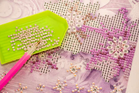 Diamond painting embroidery craft. Acrylic rhinestones and pen tool. Closeup, selective focusの写真素材