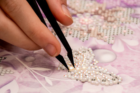 Diamond painting embroidery craft. Acrylic rhinestones, pearls and tweezers. Closeup, selective focusの写真素材