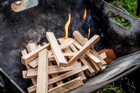Starting the camp fire with kindling in a portable foldable fire pit. Camping lifeの写真素材