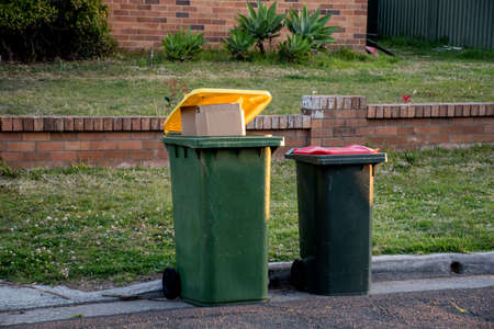 Australian garbage wheelie bins with colourful lids for general and recycling household waste on the street kerbside for council rubbish collectionの写真素材