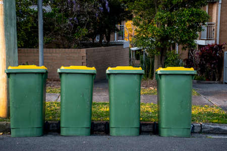 Australian garbage wheelie bins with colourful lids for recycling household waste lined up on the street kerbside for council rubbish collectionの写真素材